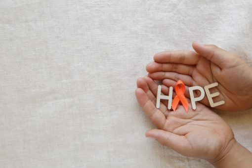 Image of a white background. The image features two hands in the right bottom corner, which are holding the letters "H, P, & E" and an orange ribbon in place of the "O" to spell hope.