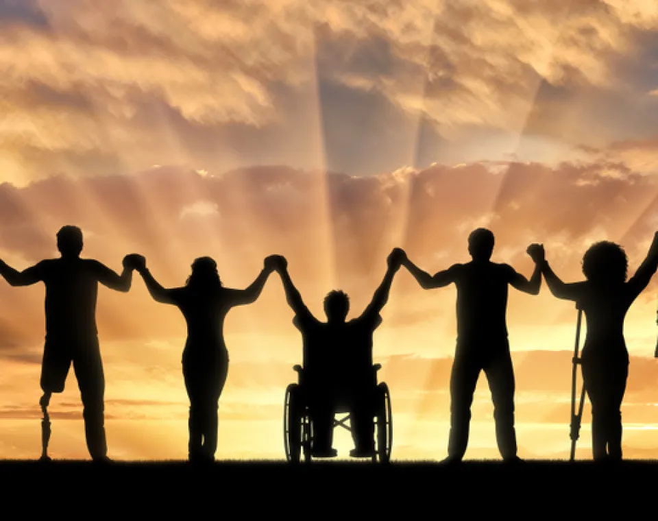 Group of people holding up hands with sunset in background