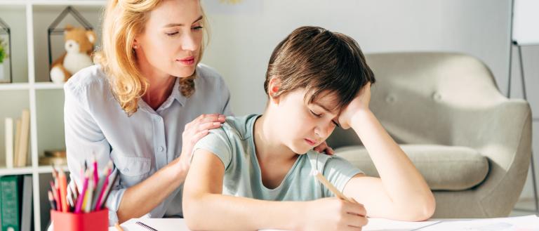 Child frustrated with school work being comforted by an adult