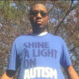 Image Description: Ryan A Lee wears a t-shirt which reads: "Shine a Light on Autism"