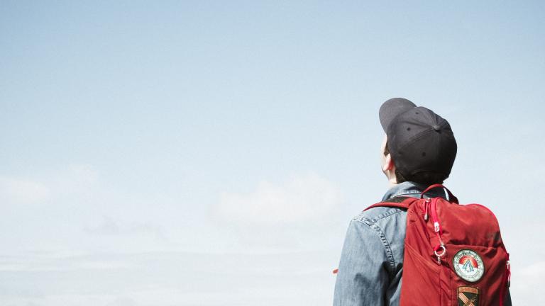 Student with backpack staring into the empty sky