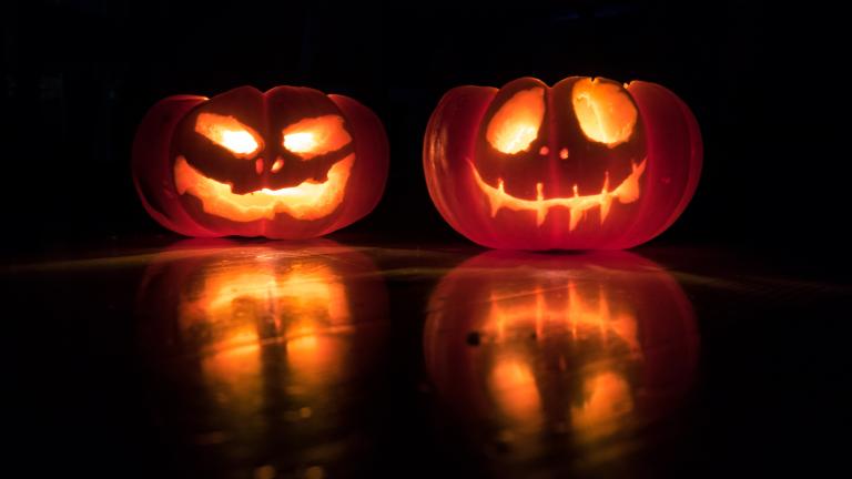 two carved pumpkins lit up. One with a goofy face and the other with a scarier more serious face.