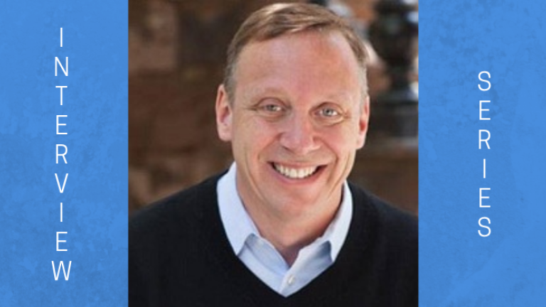 image of Dr. David S. Feldman. He is wearing a black v-neck sweater and a white button collared shirt under the sweater. He is smiling at the camera.