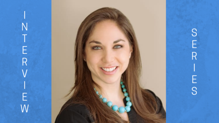 Image of Dr. Laura Phillips. She has brown hair and is wearing a black V-neck sweater with a mint green bauble necklace. She is positioned in portrait mode. Facing right.