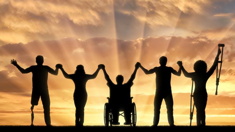 Individuals holding hands facing a sunset